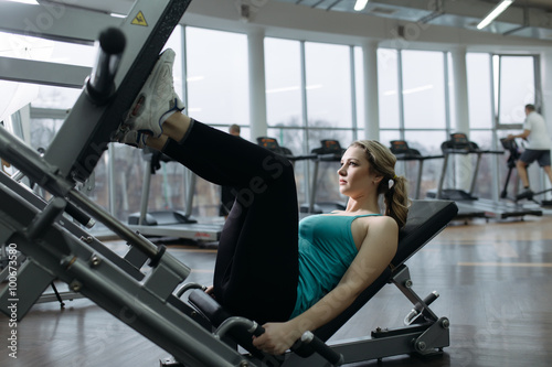 Beginner sportswoman doing exercise for leg in gym