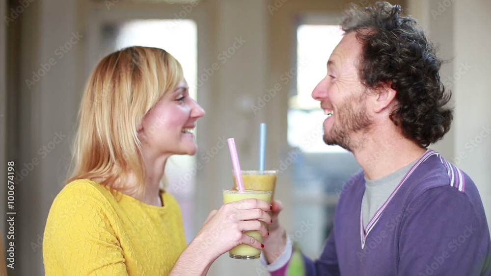 Happy couple toasting and drinking fruit smoothie Happy couple toasting and drinking fruit smoothie