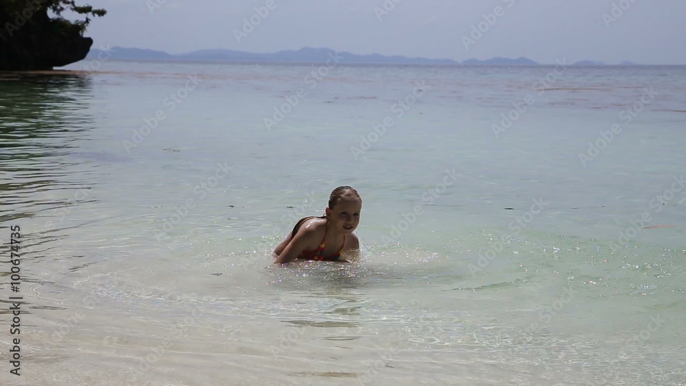 Young girl playing in the wave with spray.Girl on a tropical beach, playing with a water spray.Travel concept.Family,summer vacation. Young girl playing in the wave with spray.Girl on a tropical beach, playing with a water spray.Travel concept.Family,summer vacation.