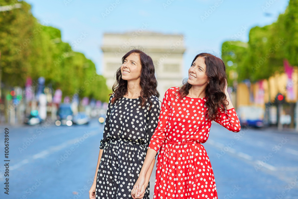 Naklejka premium Beautiful twin sisters in front of Arc de Triomphe