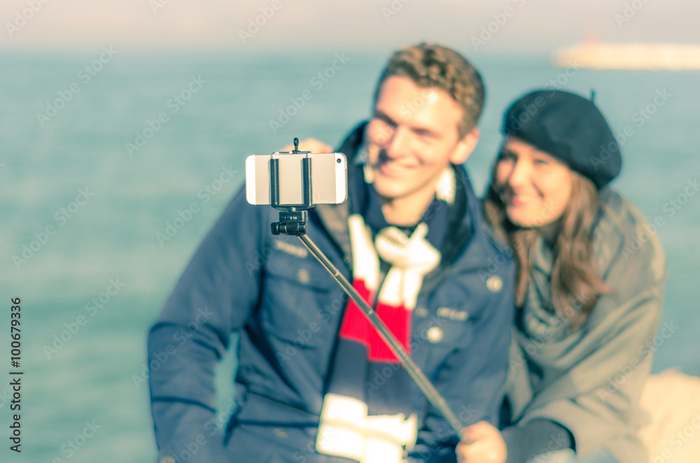 Loving in couple is taking a selfie with their stick - caucasian people - people, lifestyle and technology concept
