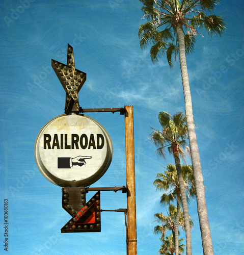 aged and worn vintage photo of railroad sign with palm trees