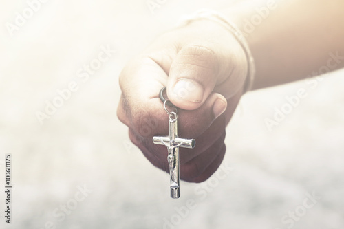 Hand with a rosary against gray background, religious concept.process in vintage color tone