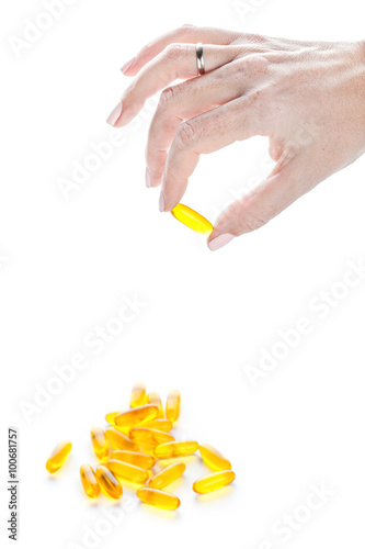 Soft gels pills with Omega-3 oil in fingers closeup on white