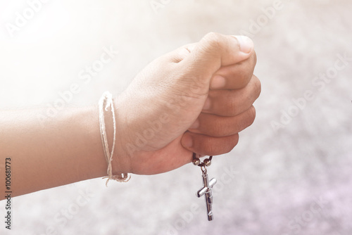 Hand with a rosary against gray background, religious concept.process in vintage color tone