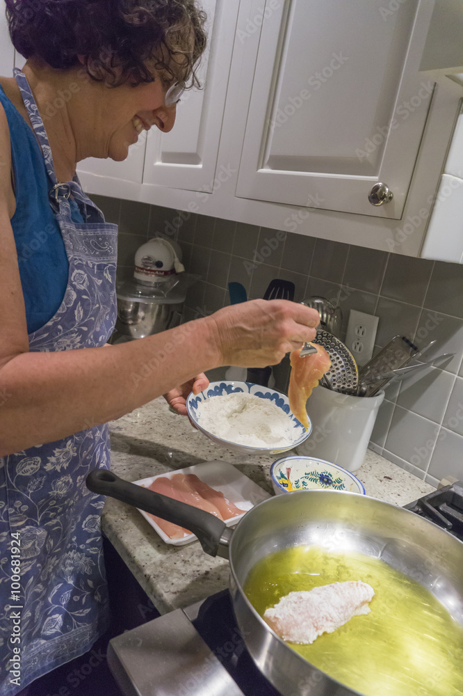 woman preparing breaded chicken for a recipe 

