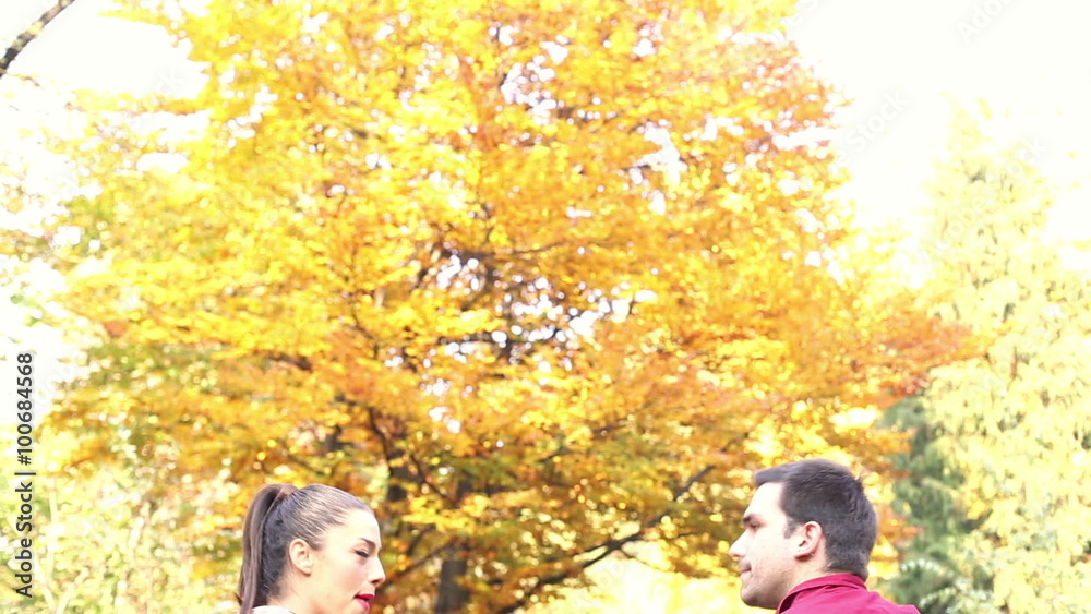 Couple sitting on park bench, man playing guitar while woman singing Couple sitting on park bench, man playing guitar while woman singing