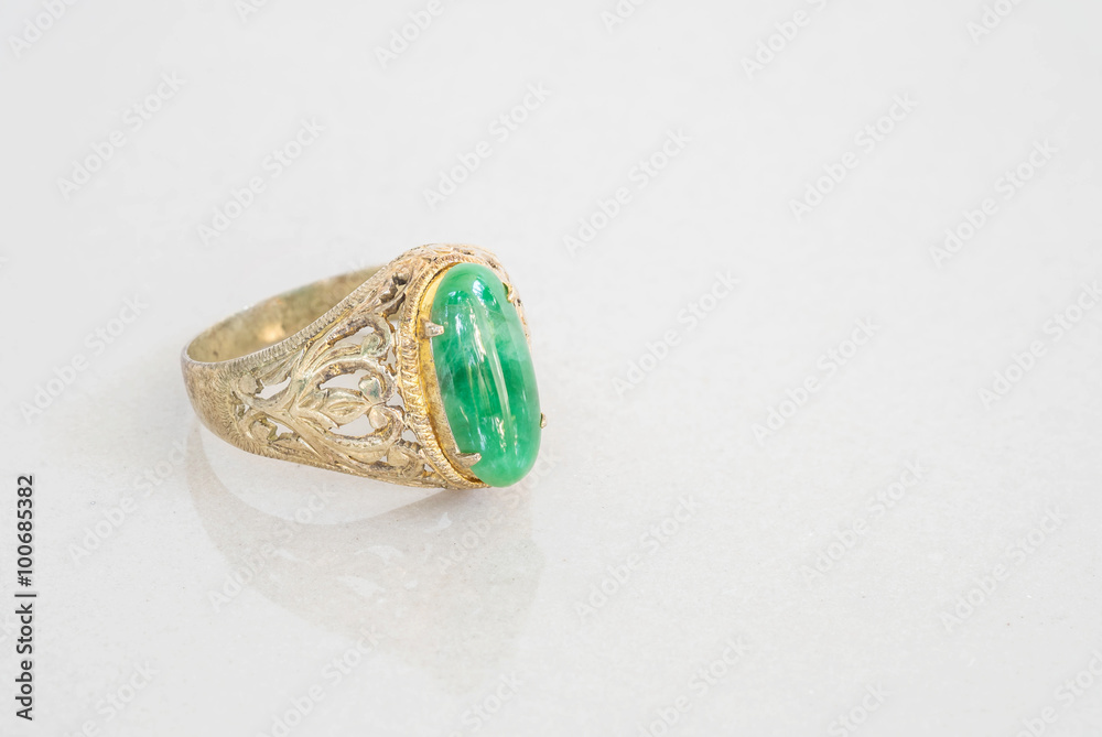 Closeup old green jade ring on blurred marble stone floor texture background Closeup old green jade ring on blurred marble stone floor texture background