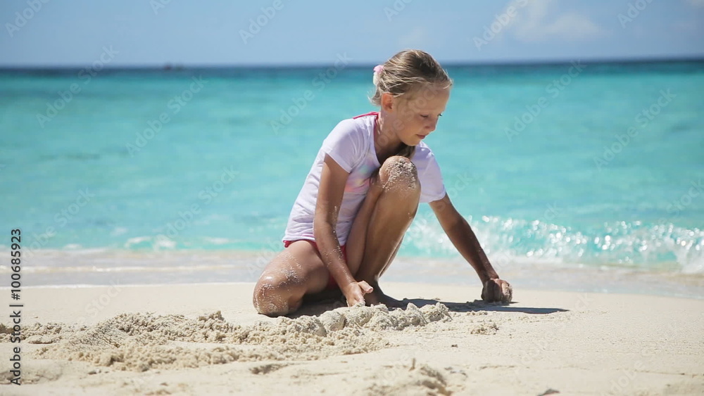Young girl playing on a tropical beach with seashells, sand and corals.little girl playing with sand on tropical beach.Travel concept.Family,summer vacation. Young girl playing on a tropical beach with seashells, sand and corals.little girl playing with sand on tropical beach.Travel concept.Family,summer vacation.