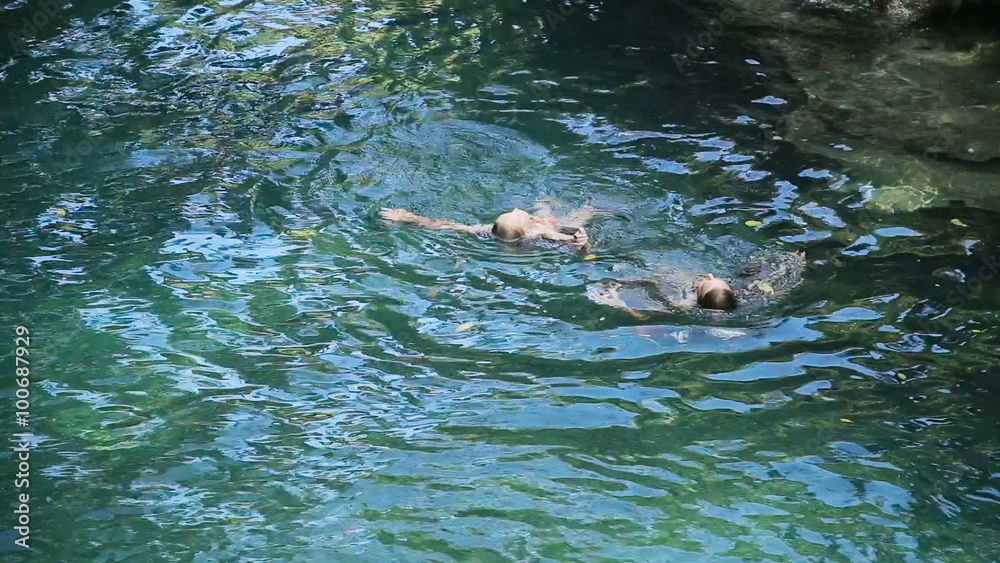 Young girls swimming in the beautiful mountain lake, enjoying a swim.Two girls are swimming in a mountain river in a canyon in the rainforest.Travel concept.Family,summer vacation.Adventure concept