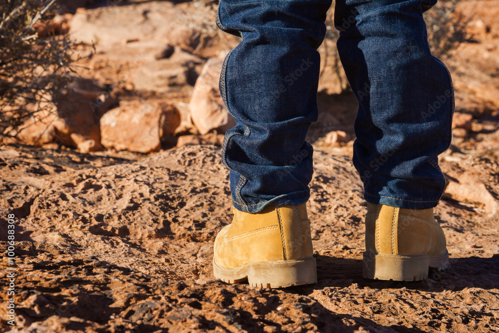 Boy in yellow shoes standing in desert, focus on left shoe