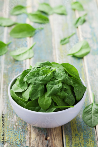 Fresh spinach leaves in bowl on rustic kitchen table, organic food