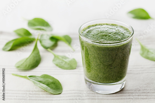 Green spinach smoothie in glass on white table, detox and diet food for breakfast