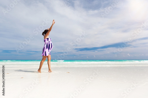 Pregnant woman walking on white beach