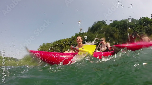 Girl splashing water on camera while sitting in a canoe