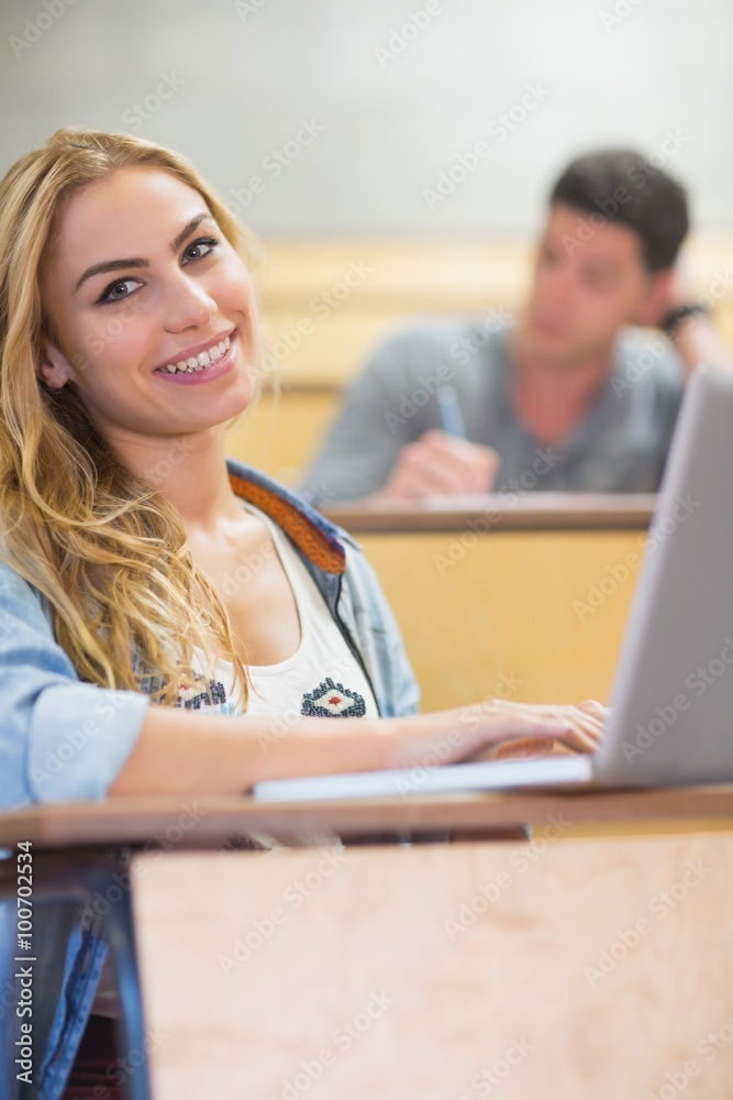 Smiling attractive student using laptop Smiling attractive student using laptop