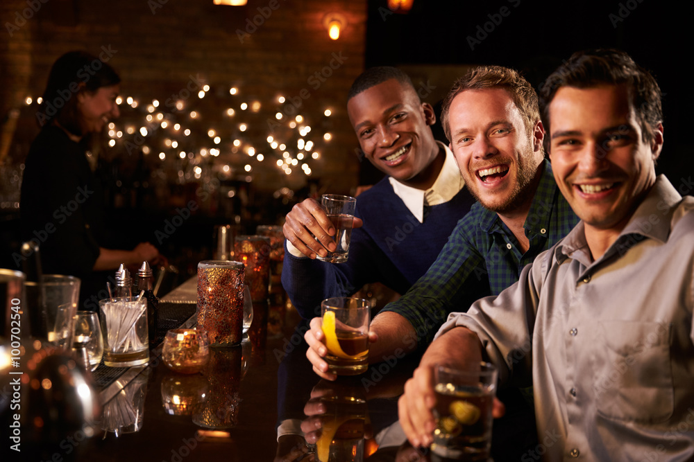 Portrait Of Male Friends Enjoying Night Out At Cocktail Bar