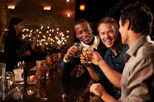 Male Friends Enjoying Night Out At Cocktail Bar