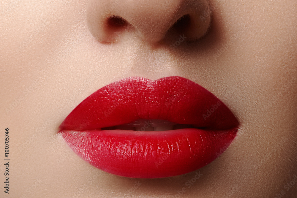 Fototapeta premium Close-up of woman's lips with fashion red make-up. Beautiful female mouth, full lips with perfect makeup. Classic visage. Part of female face. Macro shot of beautiful make up on full lips.