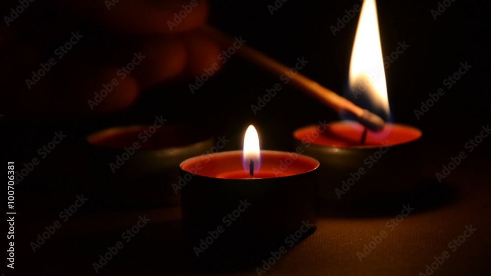 Three red candles lit by wooden match with restless flames extinguished in the end. Three red candles lit by wooden match with restless flames extinguished in the end.