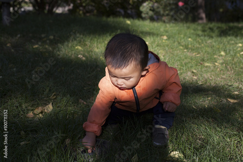 Cute Chinese baby boy studying a fountain blow hole in grass