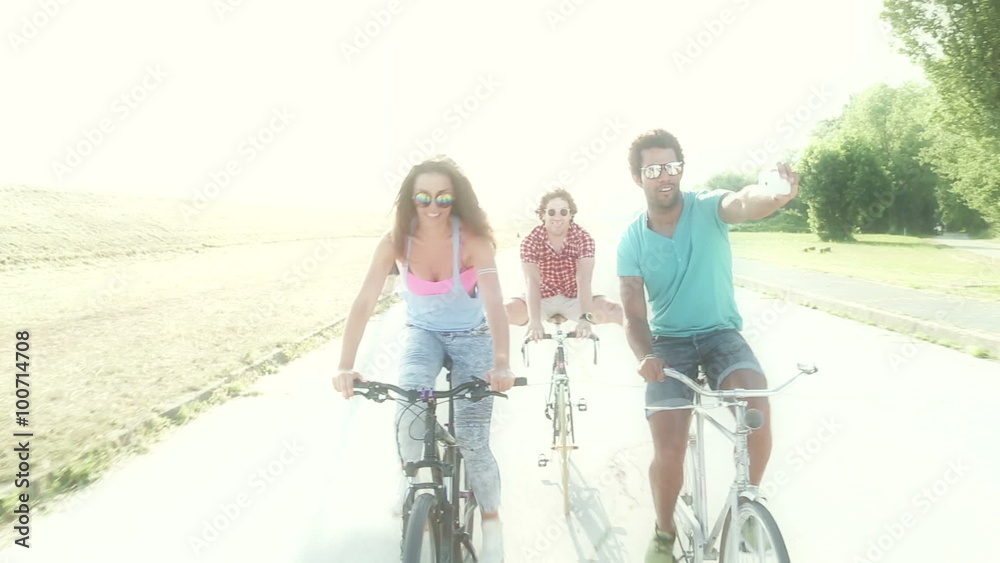 Three young adults having fun cycling and taking selfies, graded Three young adults having fun cycling and taking selfies, graded