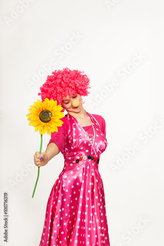 Cheerful, emotional clown in pink wig with yellow flower