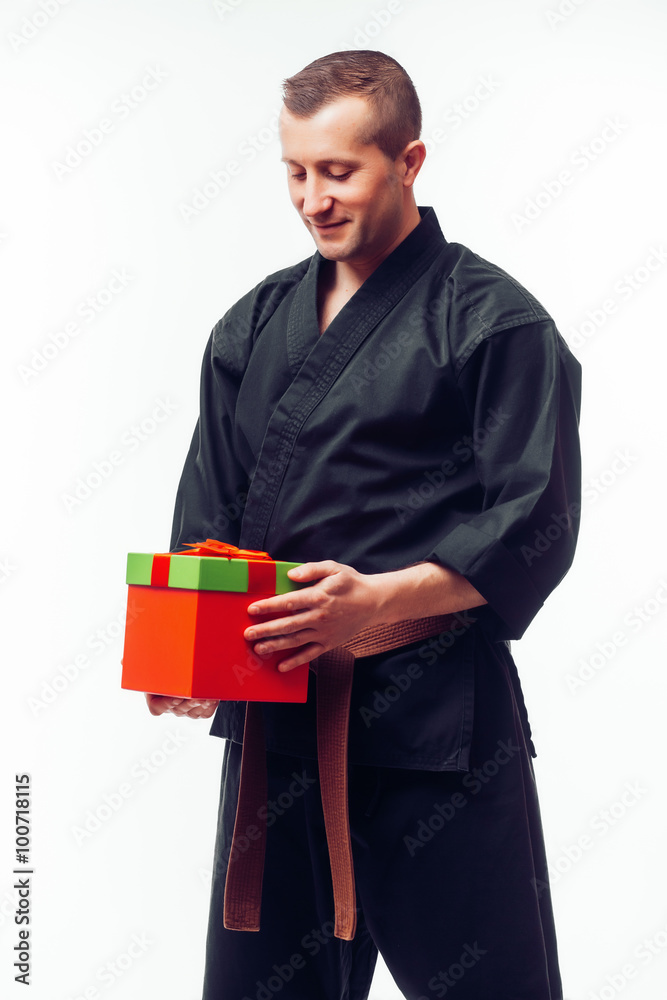 Young male with orange belt karate fighter training with gift box. Isolated on white background Young male with orange belt karate fighter training with gift box. Isolated on white background