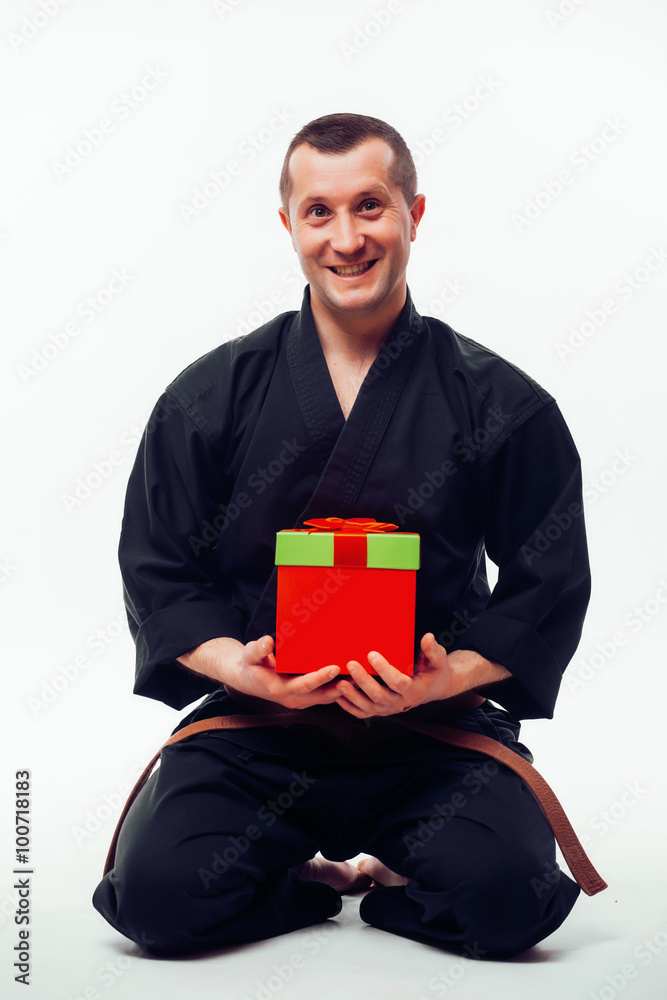 Young male with orange belt karate fighter training with gift box. Isolated on white background Young male with orange belt karate fighter training with gift box. Isolated on white background