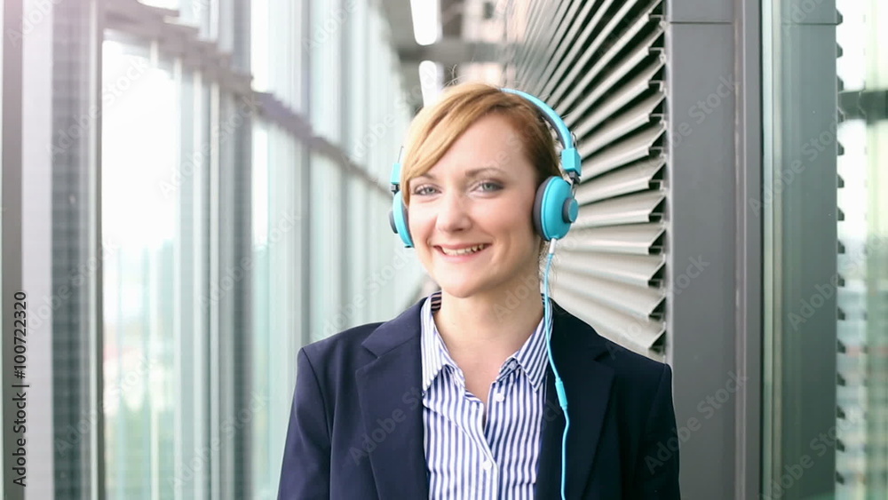 Smiling businesswoman putting on headphones and starts dancing Smiling businesswoman putting on headphones and starts dancing