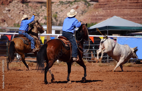 A cowboy chasing a bull with a rope on a rodeo event