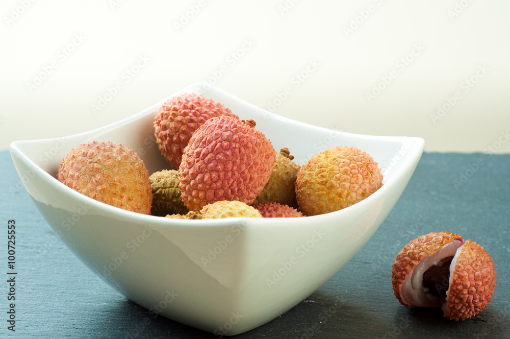 Bowl of fresh ripe lychees on a gray slate table top. Bowl of fresh ripe lychees on a gray slate table top.