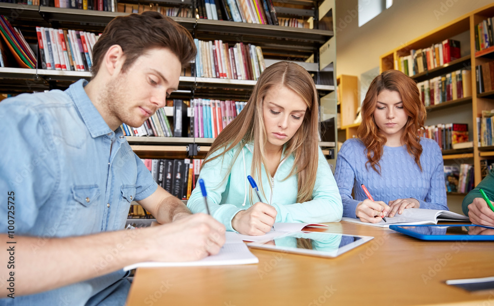 happy students writing to notebooks in library happy students writing to notebooks in library