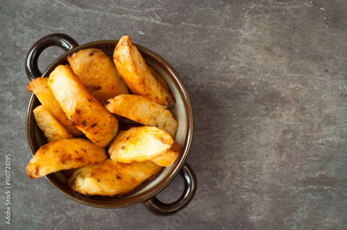 Canvas Print Bowl of chunky potato wedges fries served on a rustic stone, slate, gray table top