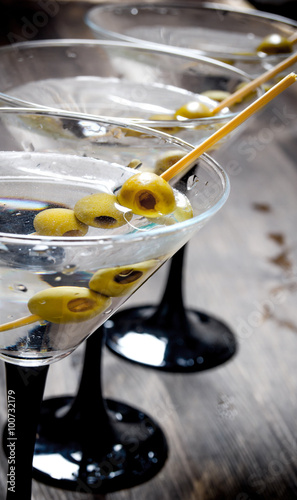 Three Martini with olives on a black table.