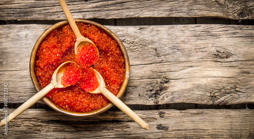 Red caviar in wooden cups with spoons.