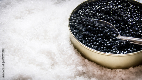 Jar with black caviar and spoon of salt. photo