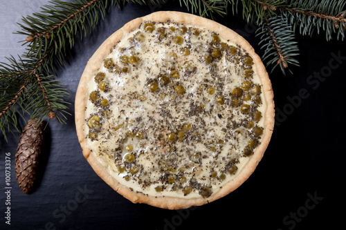 Pie with filling with Christmas tree branches on a black backgro photo