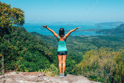 Girl on the view poit of the mountain, standing back in front of
