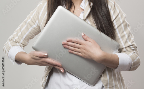 beautiful young office worker holding gray computer