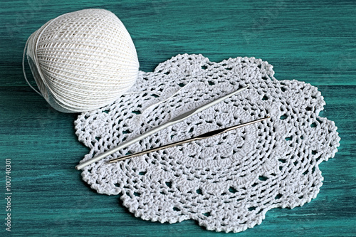 Knitting. Crochet doily, a ball of yarn and two hooks on a blue wooden background. 