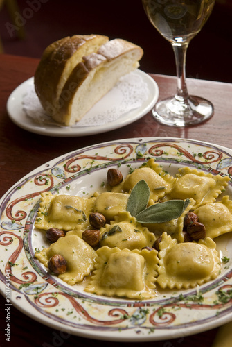 Butternut squash ravioli with olive oil, hazelnuts and sage leaves with sliced bread and red wine.