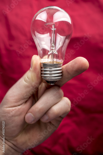 Tungsten bulb held in the hand on a red background and looks like a human skull