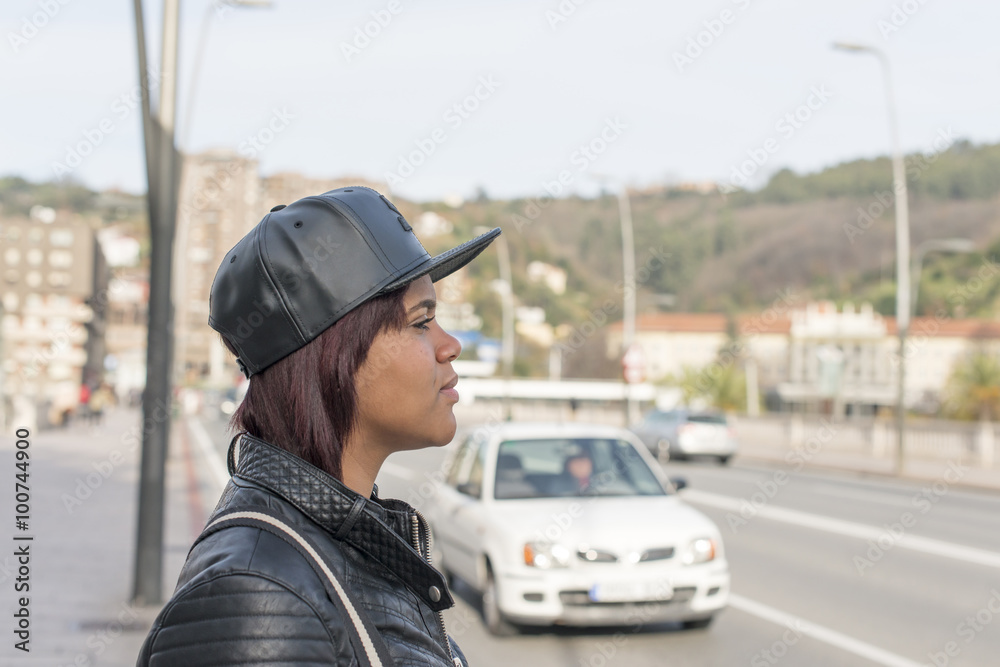 Profile portrait of young woman with baseball cap in the street. Profile portrait of young woman with baseball cap in the street.
