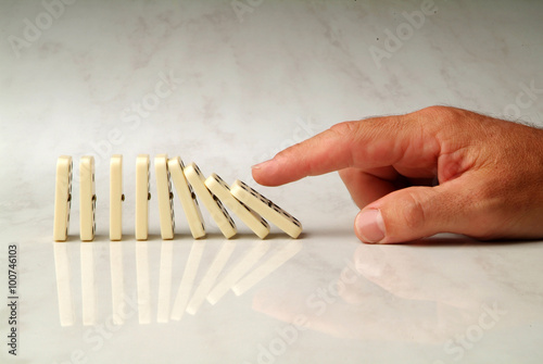 row of dominoes pushed by hand