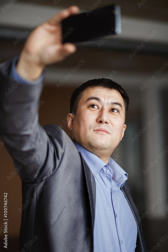 Businessman holding mobile smart phone using app doing selfie, preparing video call, wearing jacket. Selfie style photo, serious man in suit making self portrait for social networks. Businessman holding mobile smart phone using app doing selfie, preparing video call, wearing jacket. Selfie style photo, serious man in suit making self portrait for social networks.