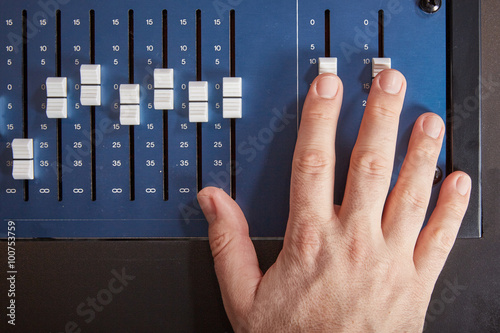 Fototapeta Fingers of audio engineer pushing the faders of an auio mixer