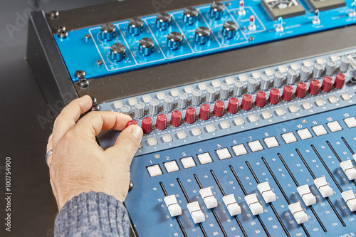 Finger of a man turning the knobs of audio console