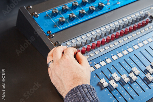 Audio engineer turning the knobs on the mixer