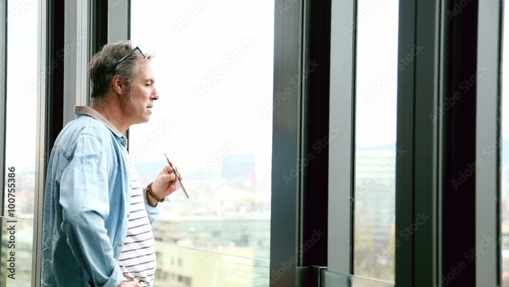 Profile of creative director standing by window, smoking electronic cigarette Profile of creative director standing by window, smoking electronic cigarette